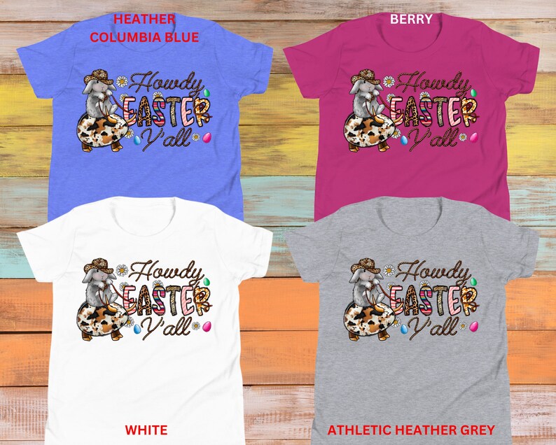 May include: Four different color t-shirts featuring a cartoon bunny wearing a cowboy hat and holding an Easter egg. The text on the shirts reads "Howdy Easter Y'all". The t-shirt colors are heather columbia blue, berry, white, and athletic heather grey.
