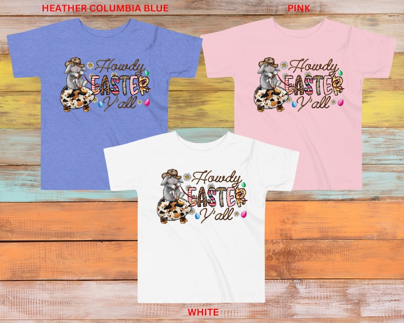 May include: Three t-shirts with a graphic of a cartoon bunny wearing a cowboy hat and riding an Easter egg. The text "Howdy Easter Y'all" is on the shirts. The shirts are in heather columbia blue, pink, and white.