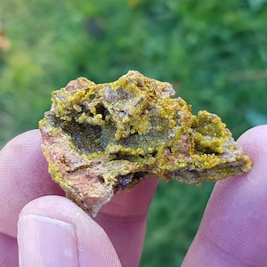 Puede incluir: Primer plano de una roca amarilla y marrón con una superficie rugosa y texturizada. La roca tiene un aspecto único, en capas, con pequeños cristales amarillos.