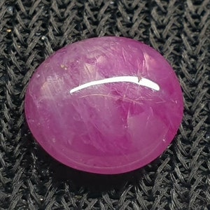May include: A pink oval-shaped gemstone with a white line running through it.