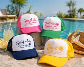 May include: Four trucker hats with white mesh backs and colorful brims. Each hat has a different design: pink with "Sunshine State of Mind", green with "Good Times Tan Lines", navy with "Salty Hair Don't Care", and yellow with "Beach Vibes".