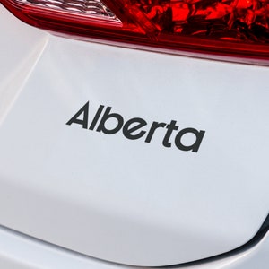 Könnte beinhalten: Ein weißes Auto mit einem schwarzen "Alberta"-Aufkleber auf der Rückseite.