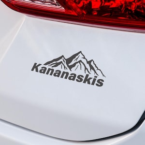 Pode incluir: Um adesivo preto e branco com uma silhueta de uma cordilheira e o texto "Kananaskis".