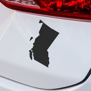 May include: A black silhouette of the state of Washington is displayed on a white car bumper.