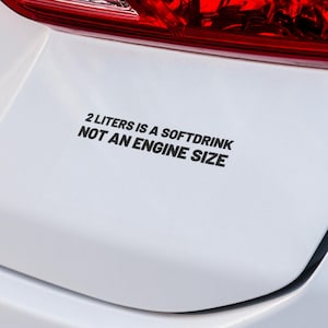 Puede incluir: Un coche blanco con una pegatina negra en el parachoques que dice "2 Litros es una bebida gaseosa, no un tamaño de motor."