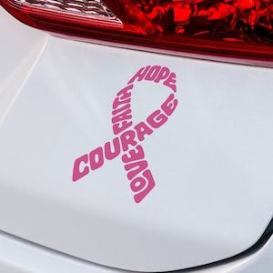 May include: Pink ribbon sticker on a white car with the words "Love, Faith, Courage, Hope" written around the ribbon.