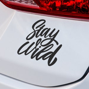 May include: A white car with a black vinyl decal that says "Stay Wild" on the rear bumper.