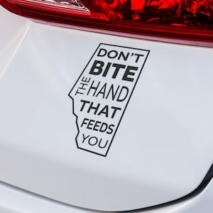 May include: Black and white sticker with the text "Don't Bite The Hand That Feeds You" on a white car.