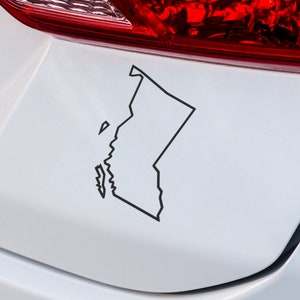 May include: A black outline of the state of Washington on a white car bumper.