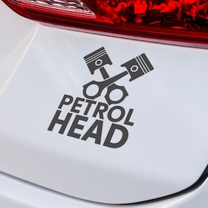 May include: A dark grey decal showing two crossed engine pistons and the words "PETROL HEAD" in a bold, sans-serif font. The decal is on a white surface, possibly a car's body.
