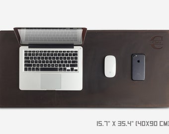 May include: A brown leather desk mat with a personalized monogram "Chris" in the upper right corner. The mat is 15.7 inches by 35.4 inches (40x90 cm) and features a laptop, mouse, and phone on top.