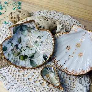 Può includere: Un set di tre tazze in ceramica con finitura opaca e macchiettata. Le tazze sono nei toni del crema, grigio chiaro e grigio scuro. Ogni tazza ha un design semplice e minimalista e un manico arrotondato.