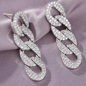 May include: A pair of silver chain link earrings with clear cubic zirconia stones. The earrings are long and dangle.