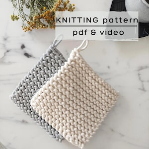 Op de afbeelding: Twee vierkante gebreide pannenlappen, één in lichtgrijs en één in crème, elk met een dikke gevlochten textuur en een kleine ophanglus. De afbeelding bevat de tekst KNITTING pattern pdf & video over het bovenste gedeelte heen.