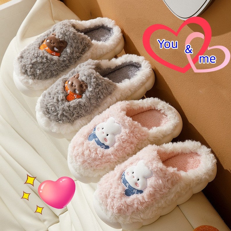 May include: Two pairs of plush slippers. One pair is gray with a bear design, the other is pink with a bunny design. Both have white soles and fluffy interiors. The image includes the text "You & me" in a heart shape.