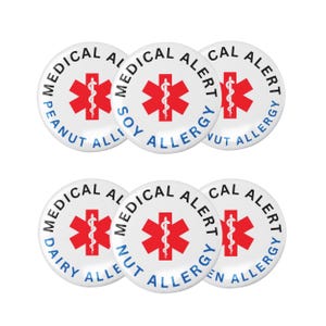 Può includere: Un gruppo di sei bottoni bianchi di allerta medica. Ogni bottone presenta un simbolo medico rosso e le parole "MEDICAL ALERT" disposte in cerchio. I bottoni indicano varie allergie, tra cui arachidi, soia, noci e latticini.