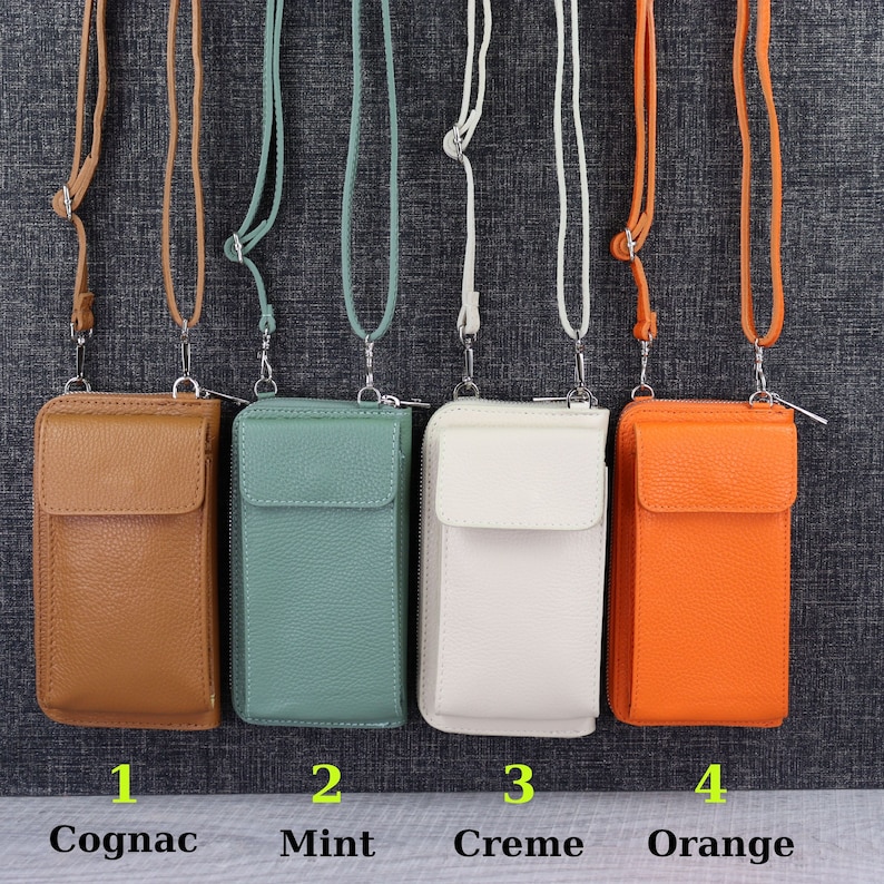 May include: Four leather phone pouches with adjustable straps in cognac, mint, creme, and orange colors. The pouches have a zipper closure and a flap with a snap closure. The pouches are numbered 1 through 4.