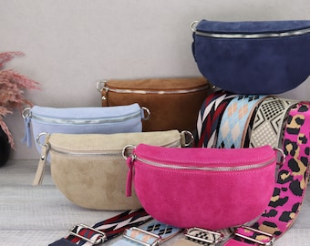 May include: Five suede fanny packs in different colors, including blue, brown, light blue, beige, and pink, with various patterned straps.