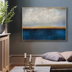 Puede incluir: Pintura abstracta con una combinaci&oacute;n de colores azul y blanco. La pintura representa un paisaje mar&iacute;timo con una l&iacute;nea de horizonte y un cielo nublado. La pintura est&aacute; enmarcada en un marco dorado.