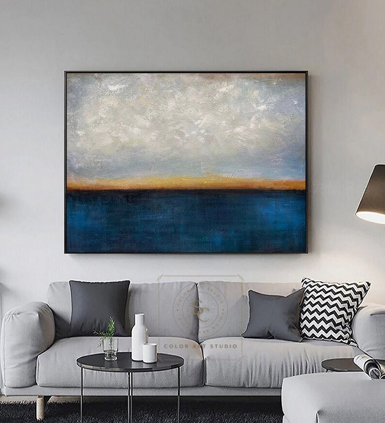 Puede incluir: Pintura abstracta de un paisaje mar&iacute;timo con un oc&eacute;ano azul, un horizonte naranja delgado y nubes blancas sobre un cielo gris claro. La pintura est&aacute; enmarcada en negro.