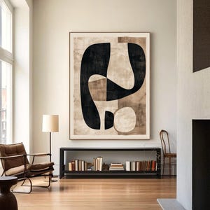 Op de afbeelding: Een groot rechthoekig wandkunstwerk met een abstracte compositie van gedurfde zwarte organische vormen, gelaagd over een getextureerde beige en lichtbruine achtergrond. Het kunstwerk is ingelijst in een dunne houten rand aan een lichte muur.