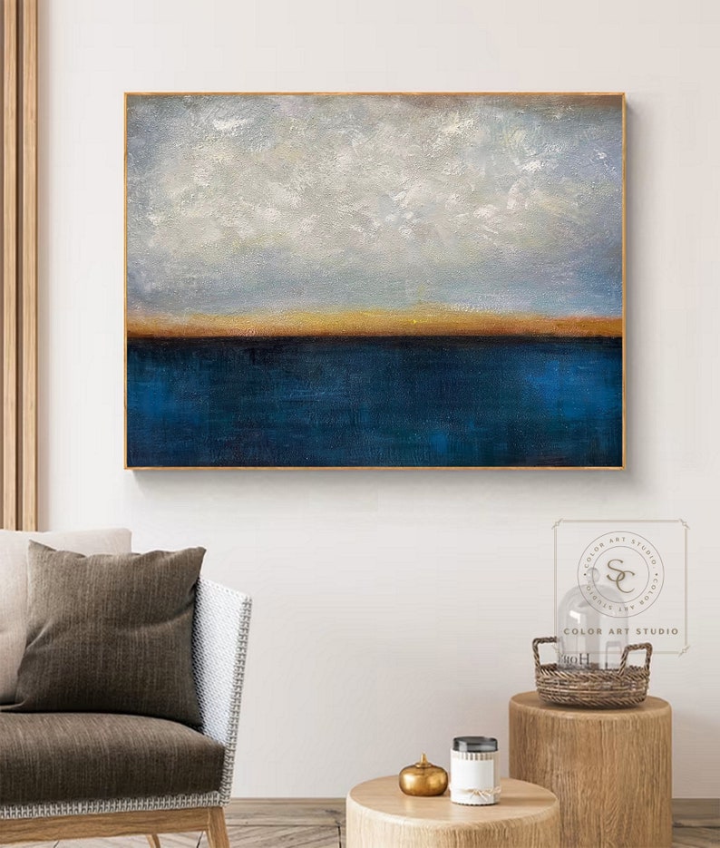 Puede incluir: Pintura abstracta con una combinaci&oacute;n de colores azul y dorado. La pintura representa un horizonte con un cielo azul y nubes blancas sobre un cuerpo de agua azul con una fina l&iacute;nea dorada que separa el cielo y el agua.