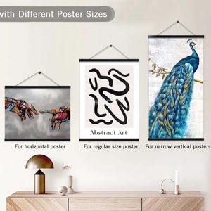 Pu&ograve; includere: Tre poster di diverse dimensioni appesi a una parete bianca utilizzando un sistema di sospensione con binari neri. I poster presentano un dipinto astratto colorato, un dipinto astratto in bianco e nero con il testo "Abstract Art" e un dipinto di un pavone con piume blu e verdi.