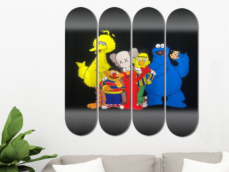 Peut inclure: Ensemble de quatre planches de skate noires avec des personnages de Sesame Street, dont Big Bird, Elmo, Cookie Monster et un personnage gris avec un X sur le front. Les personnages sont tous souriants et se tiennent la main.