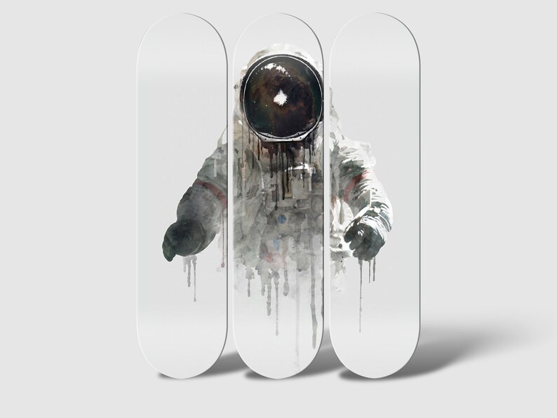 May include: Three white skateboard decks with a watercolor illustration of an astronaut in a spacesuit. The astronaut's helmet is black and the suit is white with black accents. The astronaut is depicted in a floating position with their arms outstretched.
