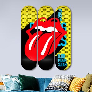 May include: Three yellow and black skateboard decks with a red tongue and lips graphic. The text on the right deck reads "25 05 16 8.00 MDNS SQUARE".