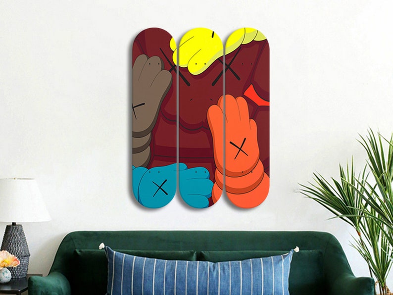 Op de afbeelding: Drie skateboard decks met een kleurrijk abstract ontwerp in een kleurenschema van rood, geel, blauw en oranje. Het ontwerp bevat een herhaald X-patroon en een cartoonachtige hand.