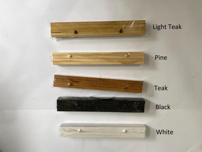 Pu&ograve; includere: Cinque cornici in legno di diversi colori: teak chiaro, pino, teak, nero e bianco. Le cornici sono tutte della stessa dimensione e forma, e sono disposte in una fila dall'alto verso il basso.