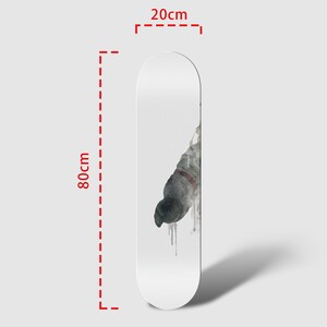 May include: A white skateboard deck with a watercolor design of a pigeon in flight. The deck measures 80 cm by 20 cm.