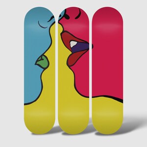 May include: Three skateboard decks with a colorful abstract design of two faces kissing. The faces are yellow, blue, and pink.