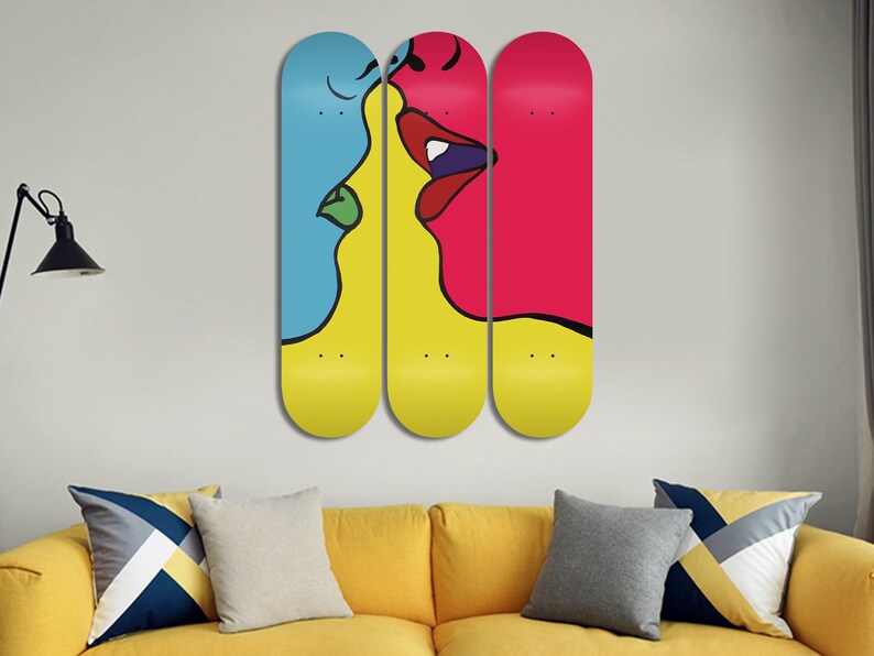 May include: Three skateboard decks with a colorful abstract design of two faces kissing. The faces are outlined in black and filled with bright colors, including yellow, blue, red, and green.