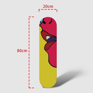 May include: A yellow and pink skateboard deck with a colorful abstract face design. The deck is 80 cm long and 20 cm wide.