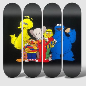 Peut inclure: Quatre planches de skate avec un fond noir et un graphisme de personnages de Sesame Street, dont Big Bird, Elmo, Cookie Monster et un personnage de la marque Kaws.
