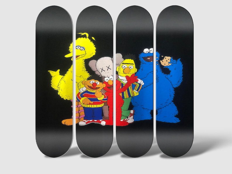 Peut inclure: Quatre planches de skate avec un fond noir et un graphisme de personnages de Sesame Street, dont Big Bird, Elmo, Cookie Monster et un personnage de la marque Kaws.
