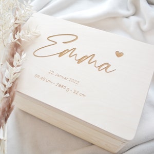 Puede incluir: Una caja de madera blanca con el nombre "Emma" grabado en la parte superior. La caja también incluye la fecha "22. Januar 2022", la hora "09:40 Uhr" y el peso y la longitud "2880g - 52 cm".