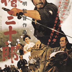 May include: A vintage Japanese movie poster for the film "The Three Outlaw Samurai" (Sanjuro). The poster features a samurai holding a sword, with the title in large red characters. The poster also includes the director's name, "Akira Kurosawa", and the studio's name, "Toho".