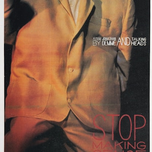 Könnte beinhalten: Filmposter für "Stop Making Sense" mit einer Person in einem beigefarbenen Anzug und dem roten Titel. Der Text "A film by Jonathan Demme and Talking Heads" ist ebenfalls enthalten.