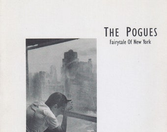 Peut inclure: Une photo en noir et blanc d'une personne regardant par une fenêtre un horizon urbain. Le texte "THE POGUES Fairytale Of New York" est imprimé sur l'image.