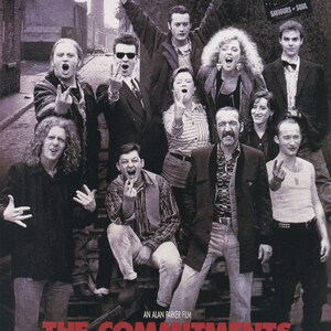 May include: Movie poster for "The Commitments" featuring a group of people, some with raised fingers, in front of a brick building. The title is in red, with the tagline "They Had Absolutely Nothing. But They Were Willing To Risk It All."
