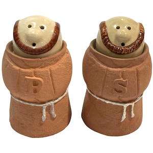 May include: A pair of ceramic salt and pepper shakers shaped like monks. The shakers are brown with tan faces and brown trim. The salt shaker has a "P" and the pepper shaker has an "S" on the front. A white rope belt is around the middle.