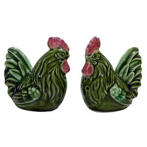 Peut inclure: Une paire de salières et poivrières en céramique en forme de coqs. Les coqs sont verts avec des crêtes et des becs rouges. Le salière a deux trous et la poivrière en a trois. Ce sont des articles de cuisine décoratifs.