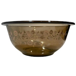 Puede incluir: Un cuenco de vidrio marrón con un diseño decorativo de flores y pájaros grabado en el exterior. El cuenco tiene un borde ancho y una forma redondeada, adecuado para la cocina.