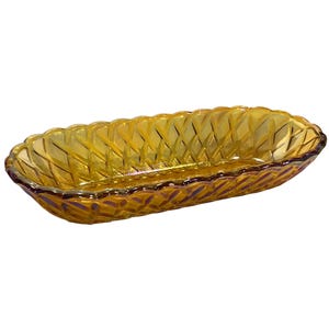 May include: An amber-coloured, oblong glass dish with a textured, woven pattern. The dish has a scalloped rim and a slightly iridescent finish, suitable for serving or display. The dish is approximately 30 cm long.