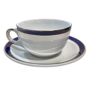 Puede incluir: Una taza de té y un platillo blancos con un borde azul y dorado. La taza y el platillo están decorados con una sola banda azul y dorada.