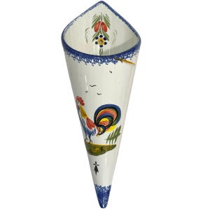 May include: A cone-shaped ceramic wall pocket featuring a hand-painted rooster with a colorful tail, green foliage, and small birds. The rim and pointed base are decorated with a blue speckled pattern, and a floral motif is painted inside the top.