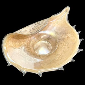 Peut inclure: Un bol décoratif en verre présentant une palette de couleurs beige clair et crème avec un motif complexe de craquelures brun foncé en forme de toile. Le bol a une forme organique asymétrique avec un bord pointu et de petites pointes.